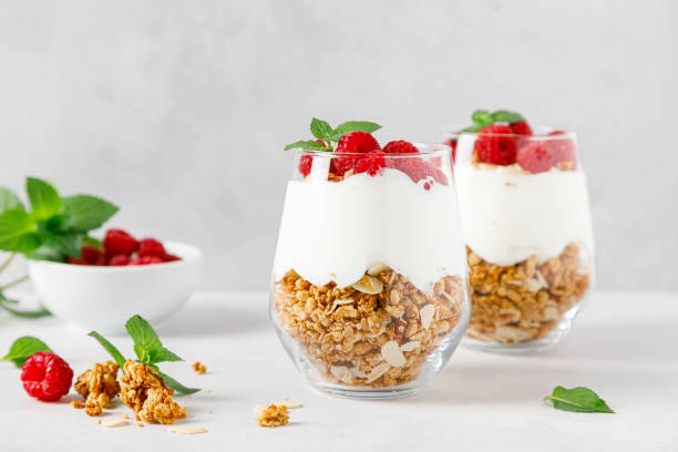 Granola with white plain yogurt and raspberry in a glass Granola with white plain yogurt and raspberry in a glass parfait photos stock pictures, royalty-free photos & images