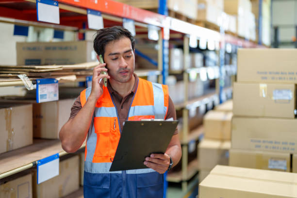 Man warehouse manager using mobile phone talking with customer. Warehouse and Logistic business concept. Man warehouse manager using mobile phone talking with customer. Warehouse and Logistic business concept. Warehouse manager checking the merchandise. dispatcher stock pictures, royalty-free photos & images