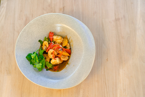 Burned shrimp Or Grilled shrimp and seafood sauce is very tasty on a white plate on white wood background.