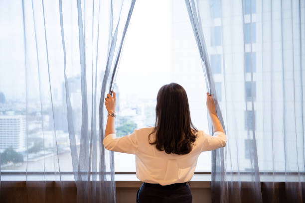 istock Woman opening a curtain. 1393631873