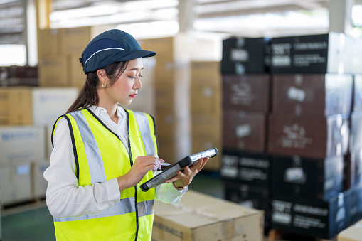 Women warehouse worker holding digital tablet checking goods and supplies on shelves with goods background in warehouse.logistic and business export concept.