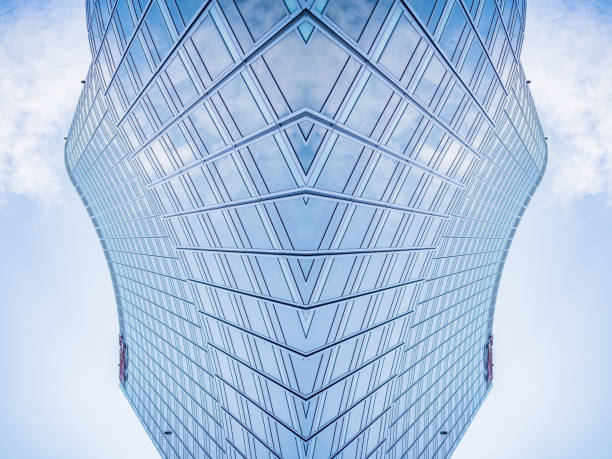 A sleek skyscraper featuring a contemporary glass facade accented with black-and-white panel elements, standing tall in the heart of downtown. Ideal for backgrounds, architectural themes, construction projects, glass facade manufacturing, advertising, design inspiration, modern architecture, and industrial production. This high-rise captures the essence of urban sophistication and innovative building techniques.