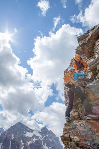 istock Climbing guide assists guest on mountain ridge 1393634815