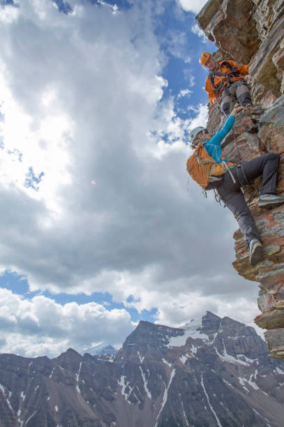 istock Climbing guide assists guest on mountain ridge 1393634818