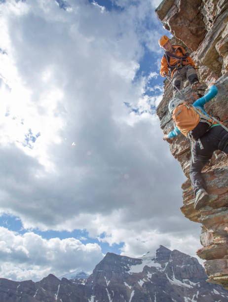 istock Climbing guide assists guest on mountain ridge 1393634820