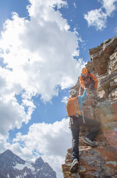 istock Climbing guide assists guest on mountain ridge 1393634841