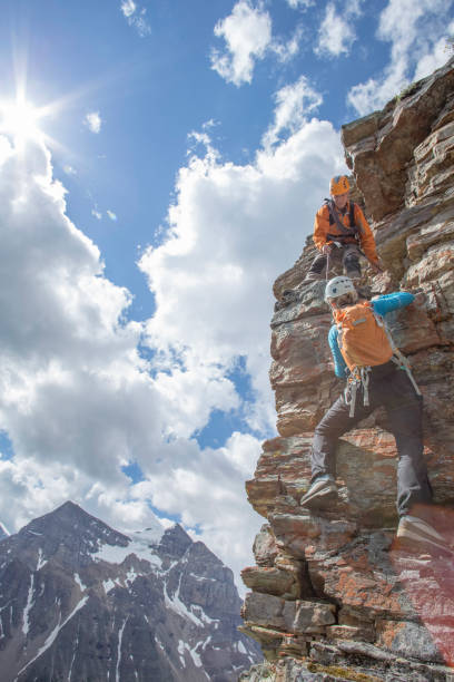 istock Climbing guide assists guest on mountain ridge 1393634849