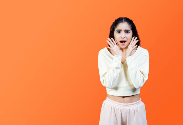 istock Shocked young woman screaming on orange background with copy space. 1393635085