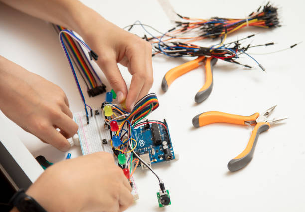 istock Side view, hands of two little kids designing electronic circuit. 1393636053
