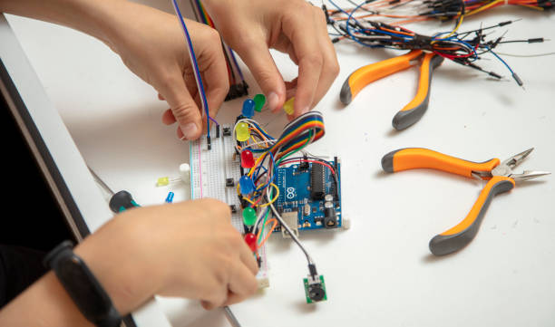 istock Side view, hands of two little kids designing electronic circuit. 1393636194