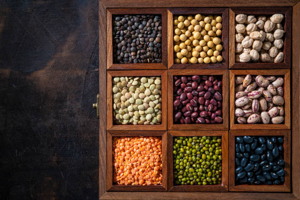 Dried Legumes assorted in a wooden box with soybean, beans, chickpeas, lentils in a row on rustic wood background