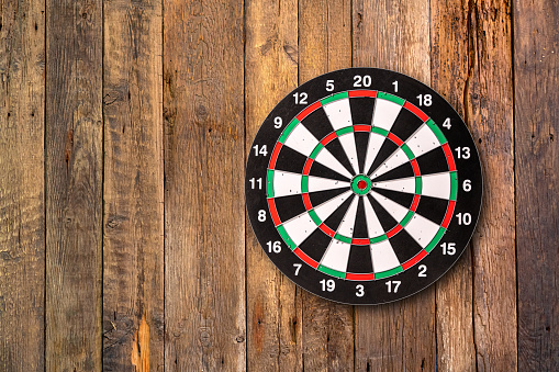 Darts target hanging on wooden background with copy space.
