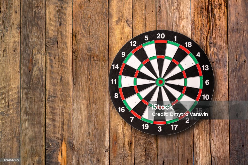 Darts target hanging on wooden background with copy space. Darts Stock Photo