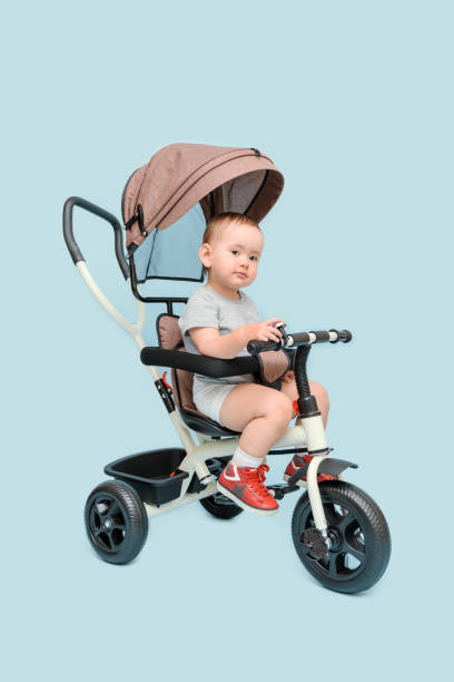 istock A pretty child is sitting on a beige tricycle on a blue background. 1393637614