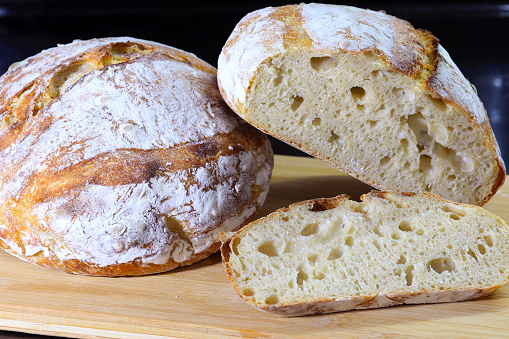 Round loaf of freshly baked homemade artisan sourdough bread on a wood