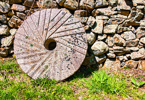 Weathered old water wheel against a stone wall at a disused mill in the picturesque small town of Prince Albert in the heart of the Karoo semidesert region in the Western Cape, South Africa, about five hours' drive from Cape Town.