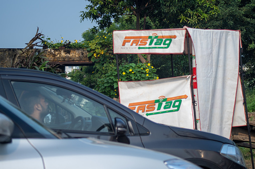 Delhi, India - circa 2021: Congested traffic jam cars in front of a toll booth showing the new RFID based payment system FASTag along with the logo for the national highway authority of India NHAI