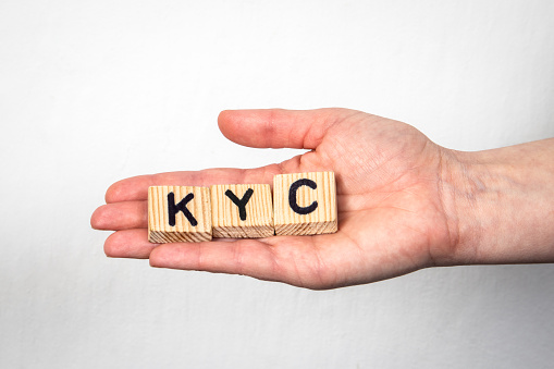 KYC Know Your Customer. Alphabet letters in a woman's hand on a white background.