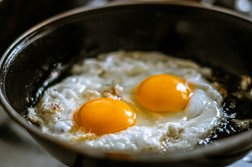 Two eggs frying in a pan with oil