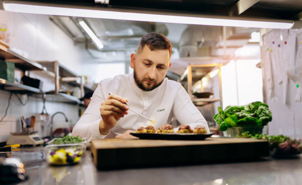 istock Chief chef serving snacks, canapes or sandviches adding finishing touch on dish before it is going to be served for restaurant guests 1393651278