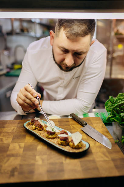istock Chief chef serving snacks, canapes or sandviches adding finishing touch on dish before it is going to be served for restaurant guests 1393651300