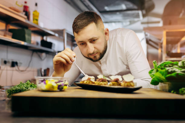 istock Chief chef serving snacks, canapes or sandviches adding finishing touch on dish before it is going to be served for restaurant guests 1393651358