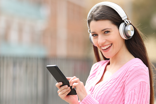 Happy teen listening to music looking at camera