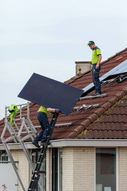 Two men installing solar panels on a tiled roof stock photo