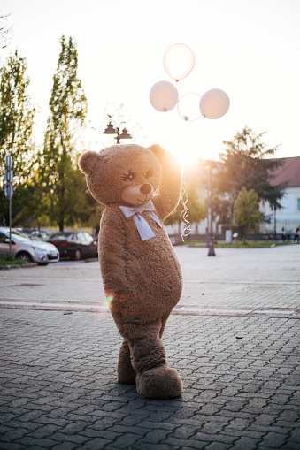 Bear mascot with baloons attending party