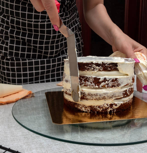 istock Applying cream with kitchen spatula on sponge cake. Close-up. Selective focus. Picture for articles about food, cooking, confectioners. 1393665310