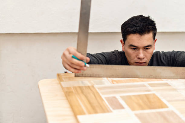 Latin carpenter between 25 and 30 years old measuring with a ruler a wooden altarpiece on a table.