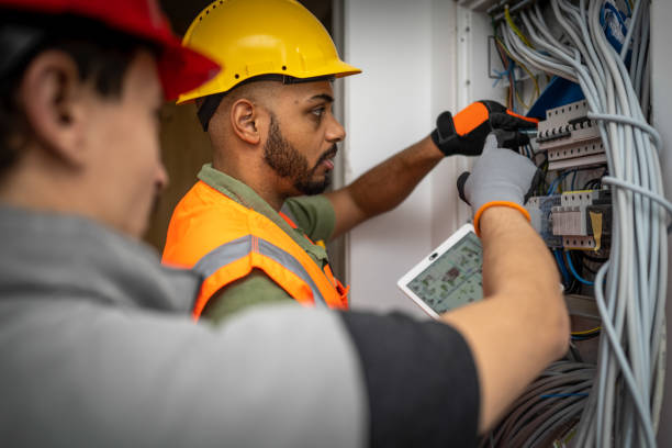 African American electrician inspecting installation, drawings on digital tablet stock photo