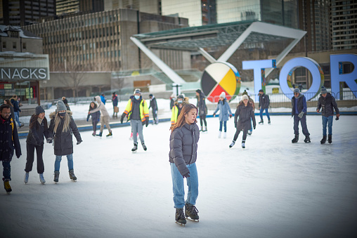 Toronto, Ontario, Canada- February 4th, 2022: An Asian lady skating at Toronto City Hall’s Nathan Phillips Square.