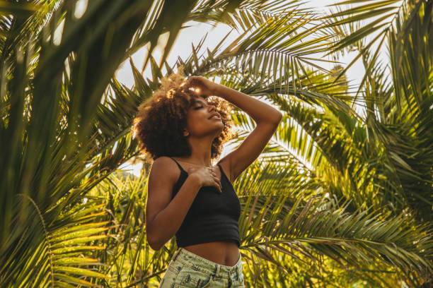 istock Pretty young afro woman among palm trees 1393672361