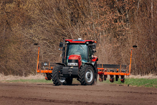 istock Spring sowing season. Farmer with a tractor sows corn seeds on his field. Planting corn with trailed planter 1393673358