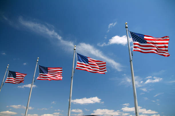 istock Four United States flags waving in the blue sky 1393673425
