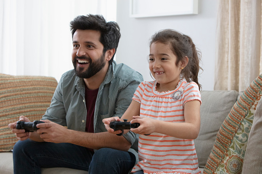 Little girl playing video game with father