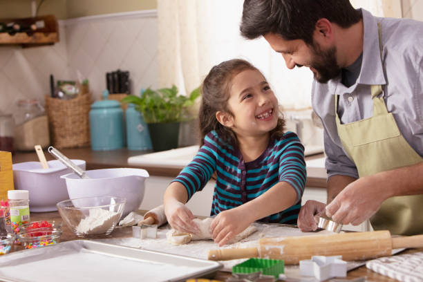 istock Little girl and father baking in the kitchen 1393673980