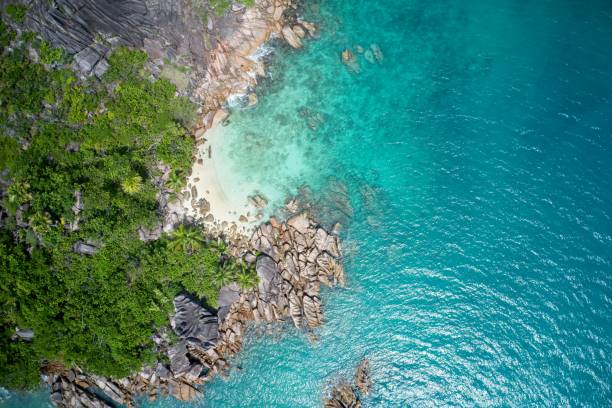 Drone field of view of spectacular blue coastline with waves and forest on Curieuse Island, Seychelles. stock photo