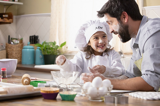 Little girl and father baking in the kitchen