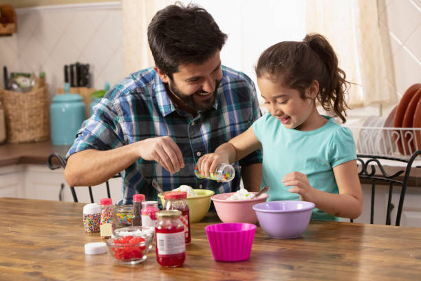 Father and daughter putting sprinkles on ice cream stock photo