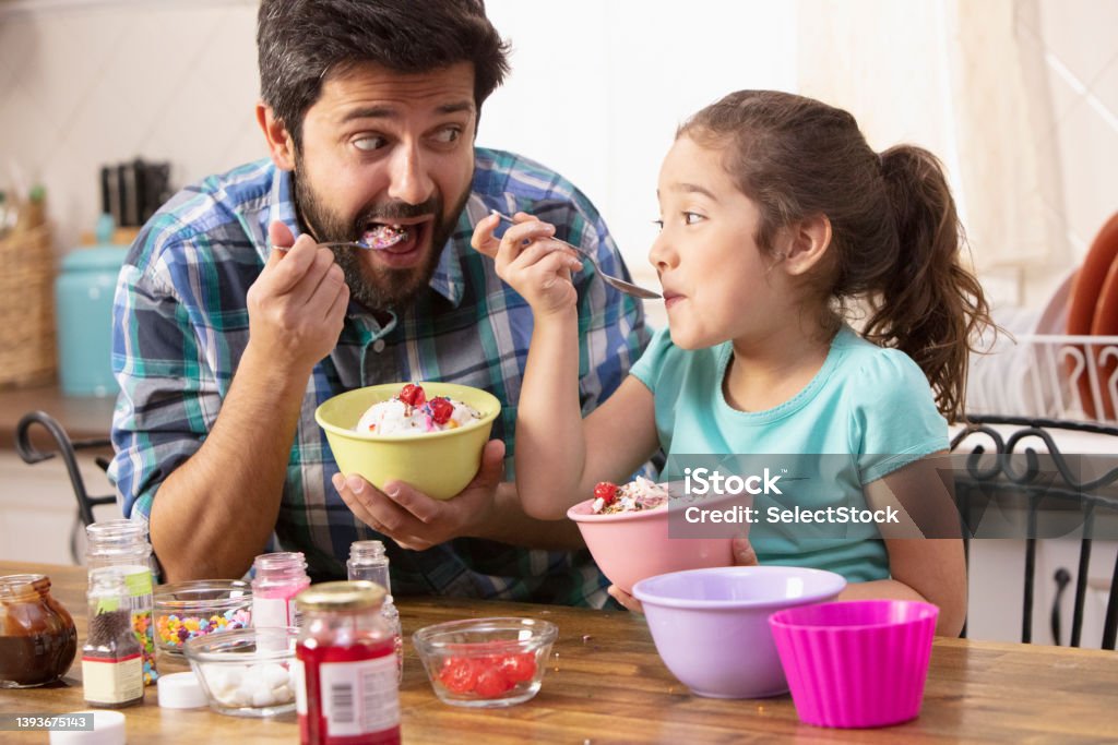 Father and daughter putting sprinkles on ice cream Ice Cream Stock Photo