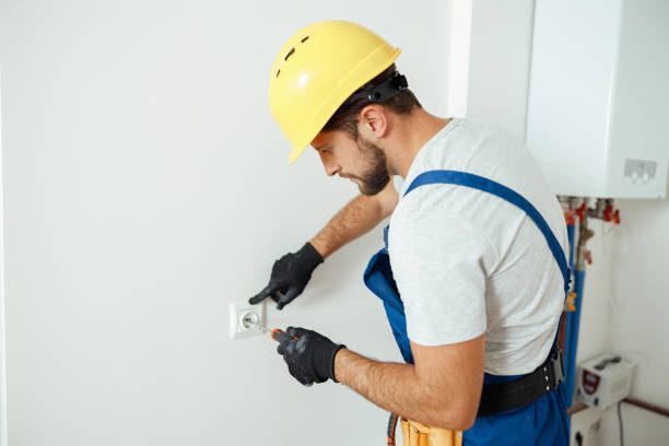 istock Male worker, professional electrician in hard hat and protective gloves using screwdriver while replacing electrical socket in a room 1393677024