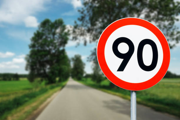 istock Speed limit sign with trees behind. Maximum ninety kilometers per hour. Safety on road background. White round sign red border line. 1393677262