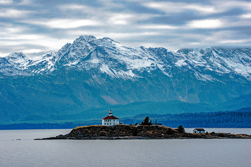 View of the Eldred Rock Lighthouse, a historic lighthouse adjacent to Lynn Canal in Alaska. It is the end of October with fresh snow on the mountains in the background. This wooden octagonal lighthouse was opened in 1905 and is 56 feet in height. The nearest city is Haines, Alaska which is reached by ferry from the south or by highway from the Yukon to the north. Historic Skagway, Alaska is also nearby. This lighthouse is in the northwestern United States of America (USA).