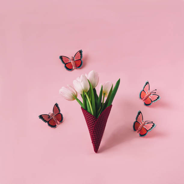 a magenta ice cream cone with white tulips and butterflies around against pastel pink background. romantic creative concept for spring summer card or banner or editorial - editorial concepts and ideas retail place store imagens e fotografias de stock