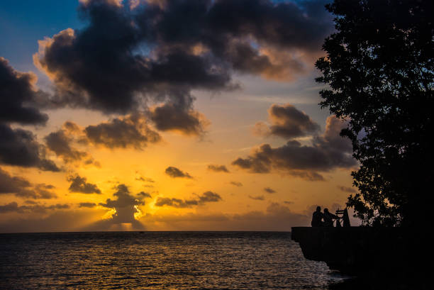 Silouhette of couple enjoying the sunset in San andres Island. The inhabitants of the Island of San Andres enjoy different customs every day to pass the time. From bathing in the sea, to playing different sports typical of the region. The inhabitants of the islands, called Raizales, have ancestral customs that are maintained for generations.