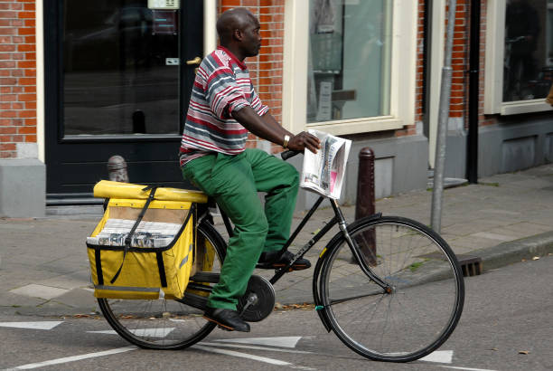 Holland, Netherlands - August 18, 2007: Postman riding a bicycle through a central neighborhood of the city of Amsterdam
