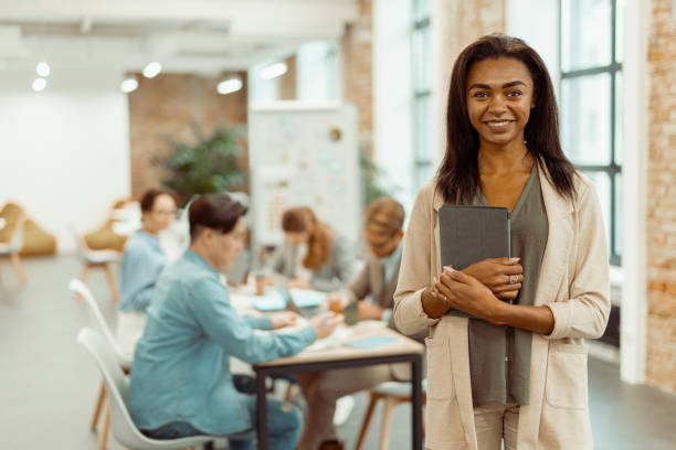 istock Smiling young woman standing with gadget in the office 1393686877