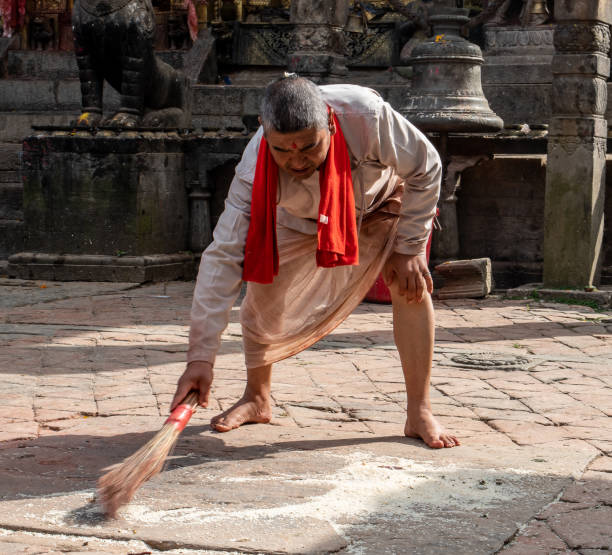 il monaco indù pulisce il cortile del tempio - changu narayan temple foto e immagini stock